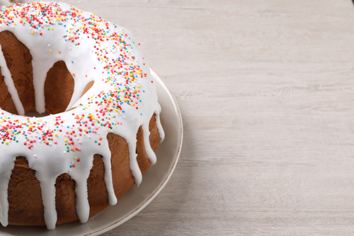 Glazed,easter,cake,with,sprinkles,on,white,wooden,table,,closeup.