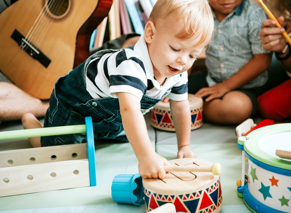 Little,kid,playing,with,a,wooden,drum,set